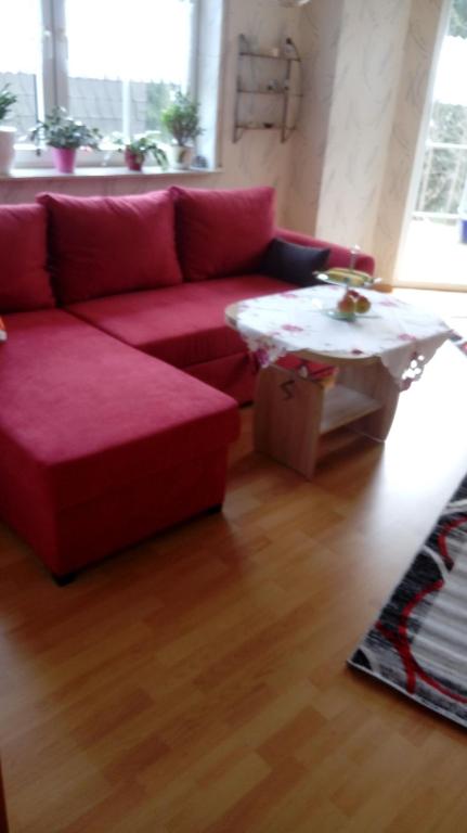 a living room with a red couch and a coffee table at Am Reichelbach schöne Natur kostenlose Stellplätze in Neuwied