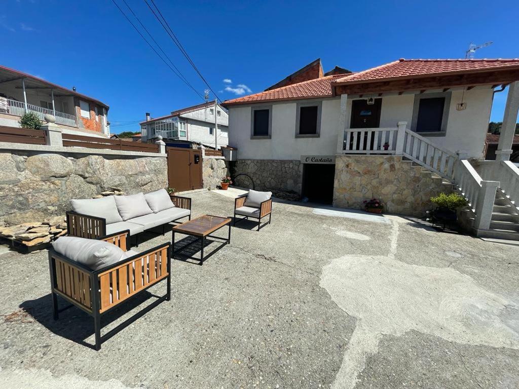 une terrasse avec 2 chaises et un canapé en face d'une maison dans l'établissement Casa O Castaño, à Carballino