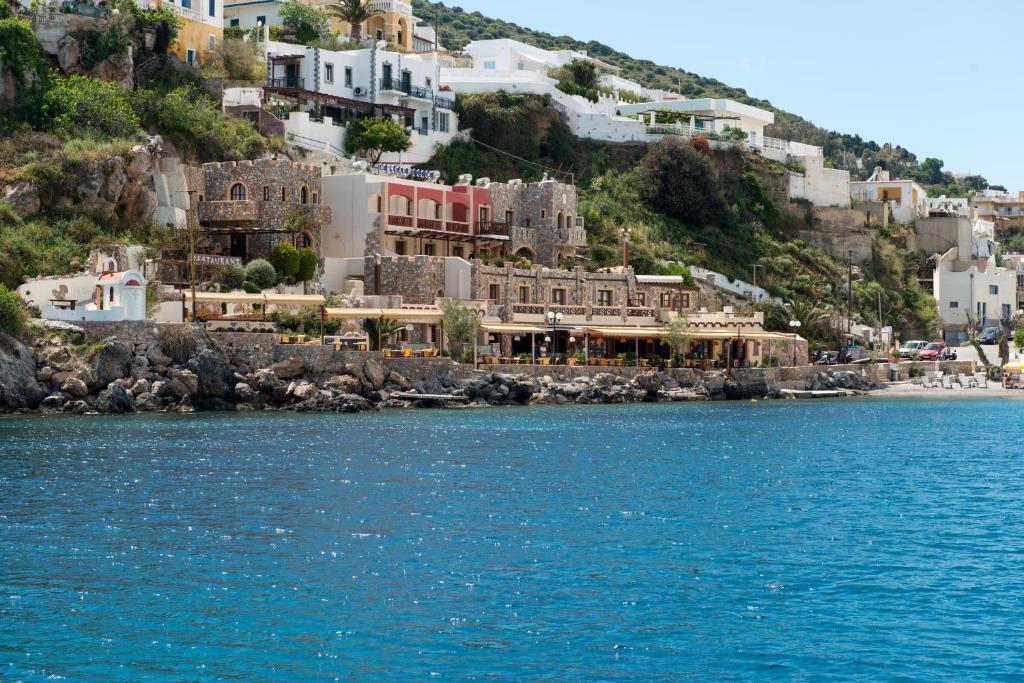 um grupo de edifícios numa colina junto à água em Castelo Beach Hotel em Panteli