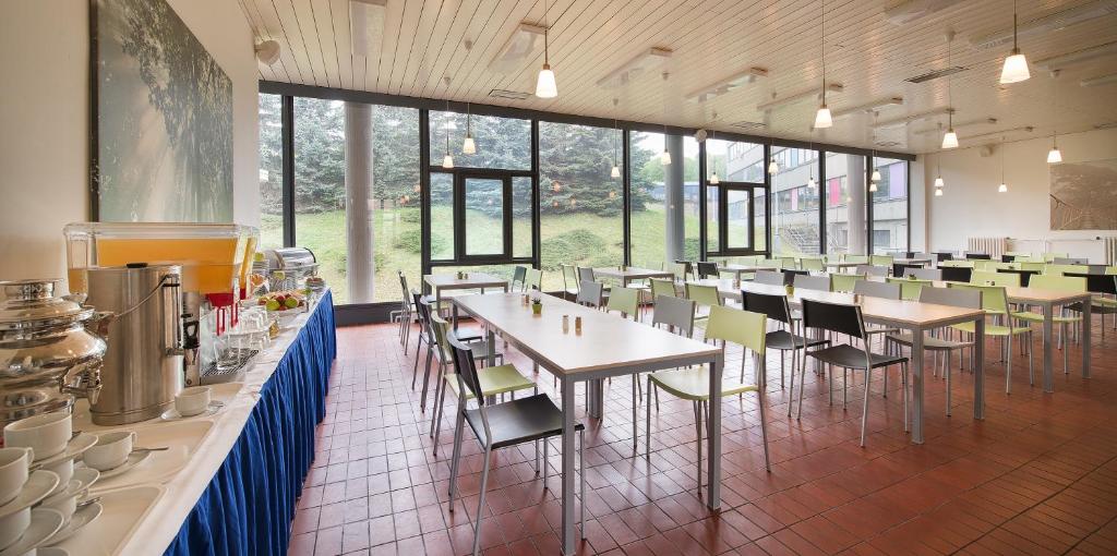 a dining room with tables and chairs and windows at Hotel Energie in Prague