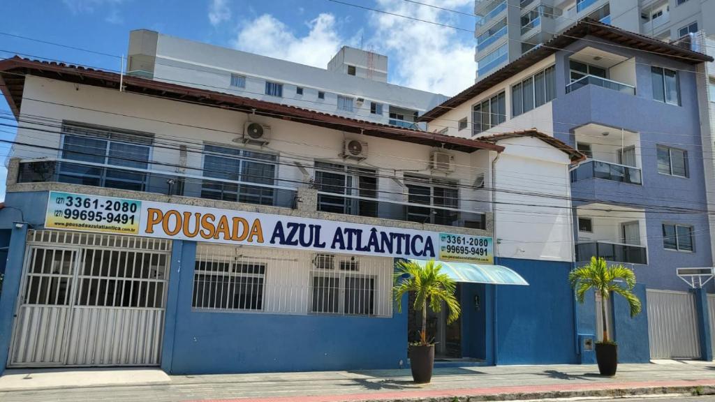 a blue and white building with palm trees in front of it at Pousada Azul Atlântica in Guarapari