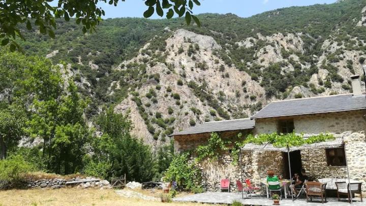 a building with a table and chairs in front of a mountain at Maison traditionnelle catalane avec jardin 