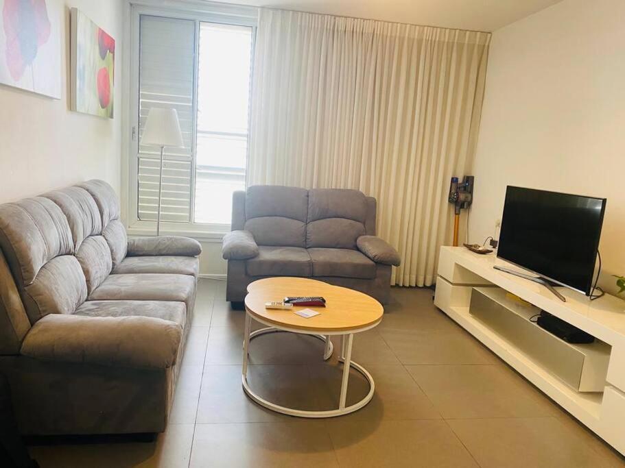 a living room with a couch and a table at Great 2 BR apartment view to the garden in Bat Yam