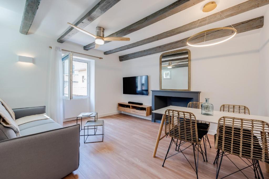 un salon avec une table, des chaises et une télévision dans l'établissement L'Escale bleue, à Annecy