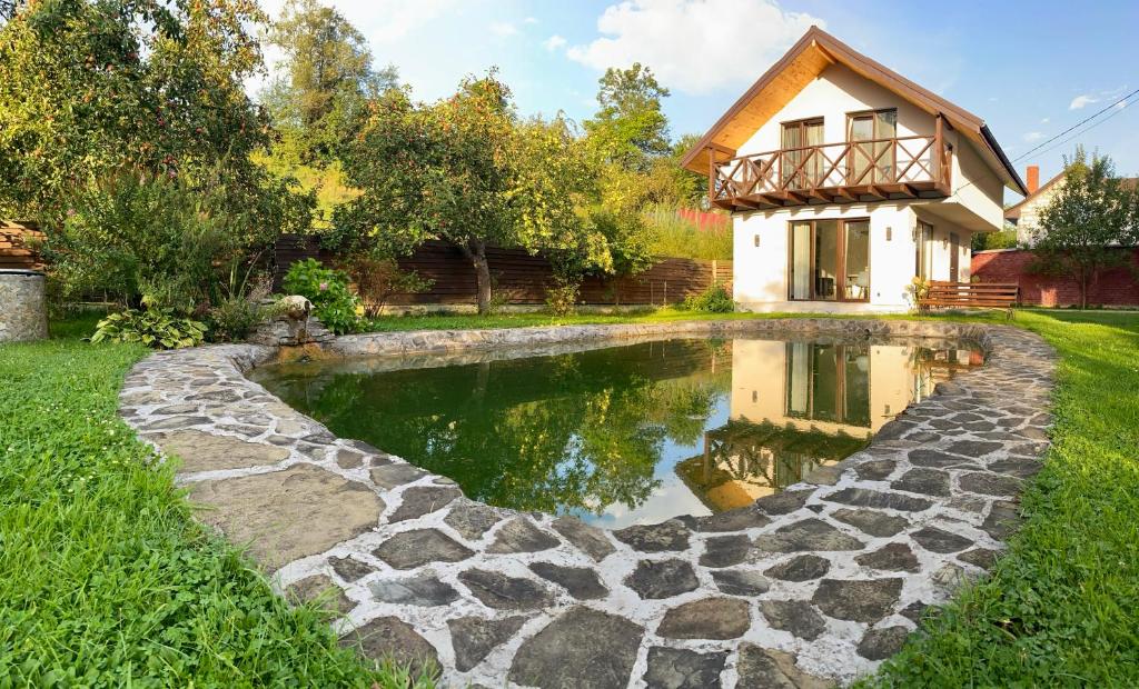 ein Haus mit einem Teich im Hof in der Unterkunft Вілла Бовч in Jaremtsche