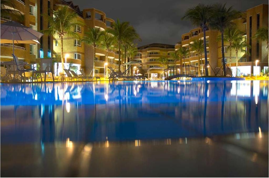 a large swimming pool with palm trees and buildings at Apartamento 2 suítes Frente à Praia de Camboinhas - Niterói - RJ - Brasil in Niterói