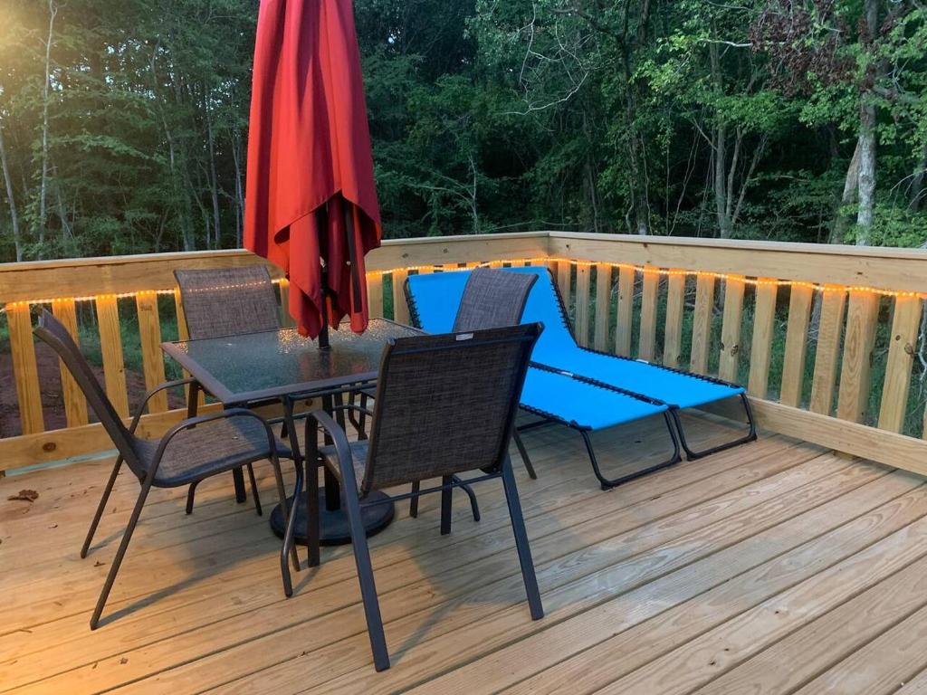 une terrasse avec une table, des chaises et un parasol dans l'établissement Cottage Too, à Iuka