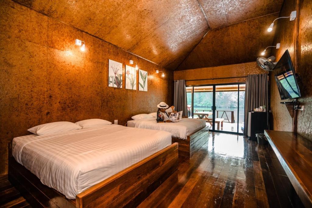a bedroom with two beds and a television in it at ธารามนตรา รีสอร์ท (Taramontra resort) in Tha Kradan
