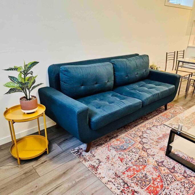 a blue couch in a living room with a table at Cozy 1 Bedroom Basement Apt in SE Calgary in Calgary