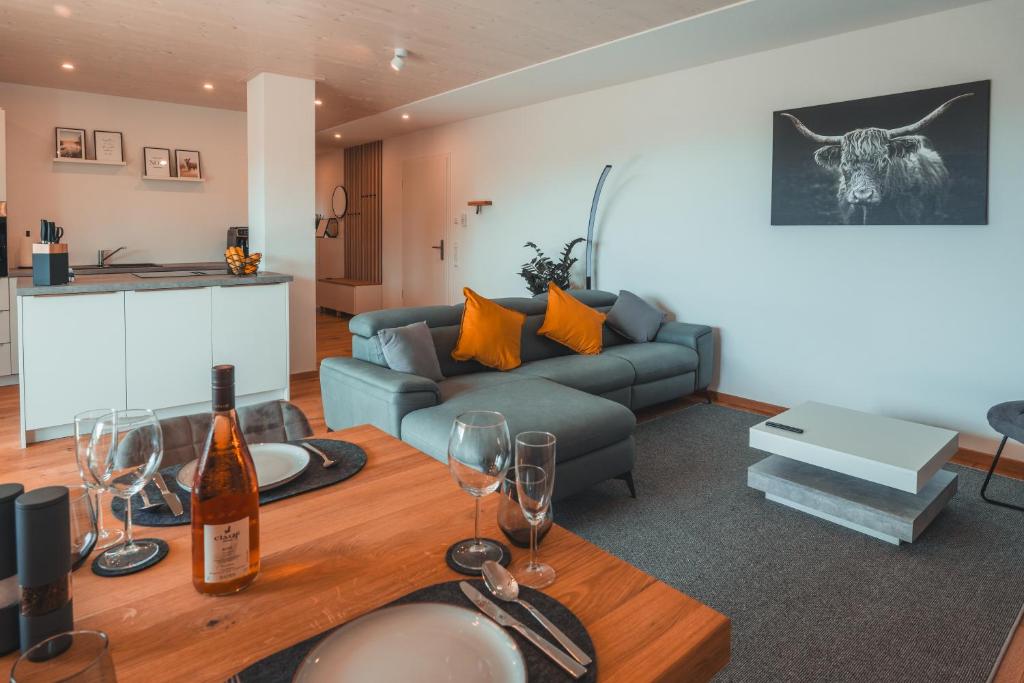 Una sala de estar con un sofá y una mesa con copas de vino. en Ferienwohnung Steinablick mit großem Balkon & Garage, en Ühlingen-Birkendorf
