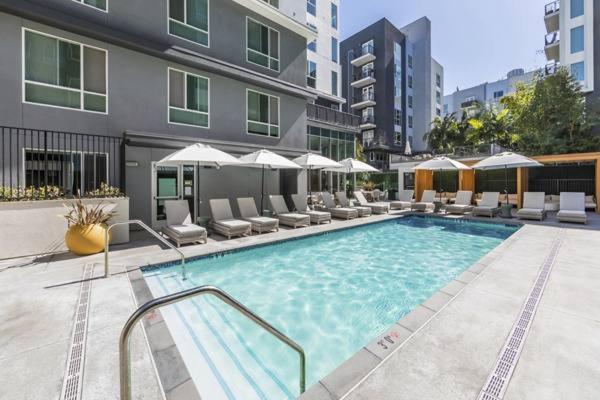 a large swimming pool with chairs and a building at DTLA Luxury Condo with Pool, Gym, Work Pods & Conference Room in Los Angeles