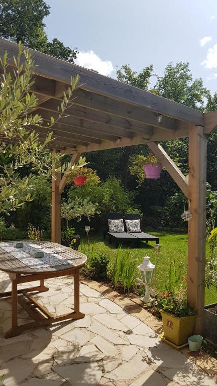 a wooden pergola with a picnic table in a garden at Chez Laurence &amp; RV in Vauréal