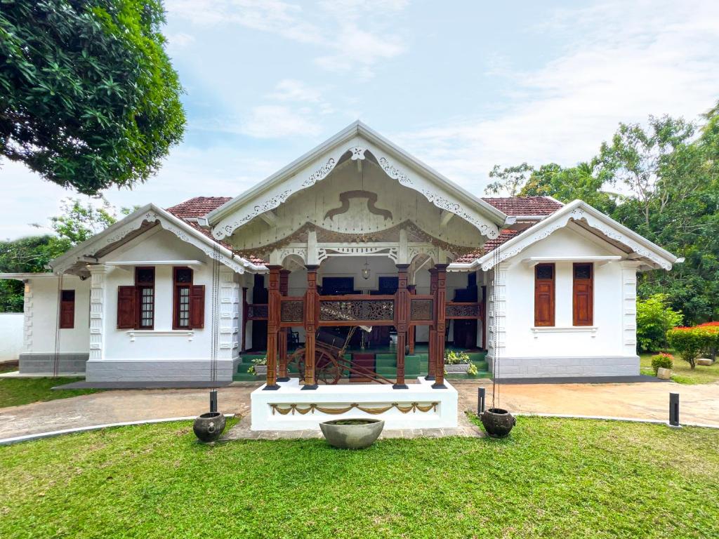une maison blanche avec une grande terrasse couverte dans une cour dans l'établissement Andiramada Walawwa, à Rambukkana