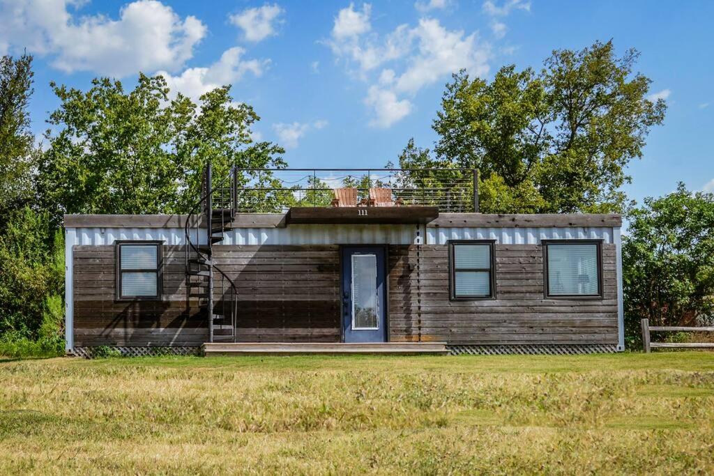a small wooden house on a grass field at New Luxury Shipping Container in Bellmead