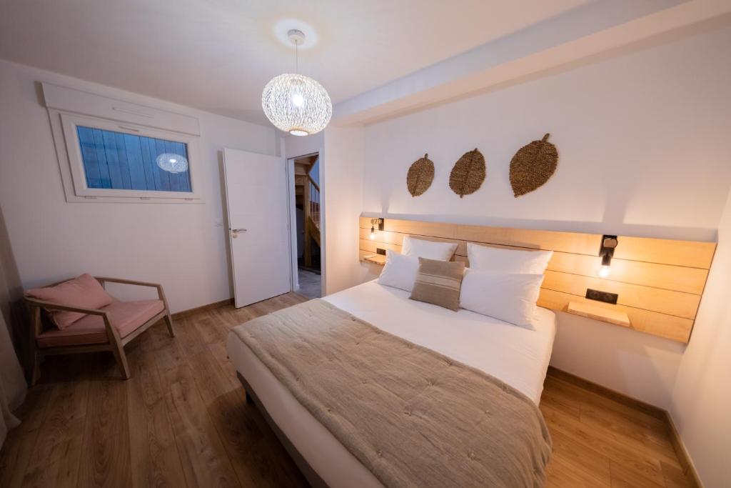 a bedroom with a large bed and a chandelier at La maison du Port Apt MARSA in Marseillan