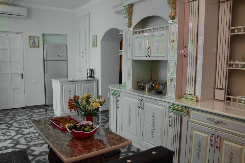 a kitchen with white cabinets and a bowl of fruit on a table at Inter Boutique Hotel in Yerevan
