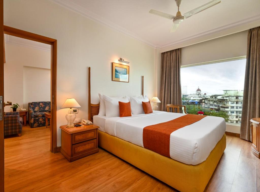 ein Hotelzimmer mit einem Bett und einem großen Fenster in der Unterkunft Fariyas Hotel Mumbai , Colaba in Mumbai