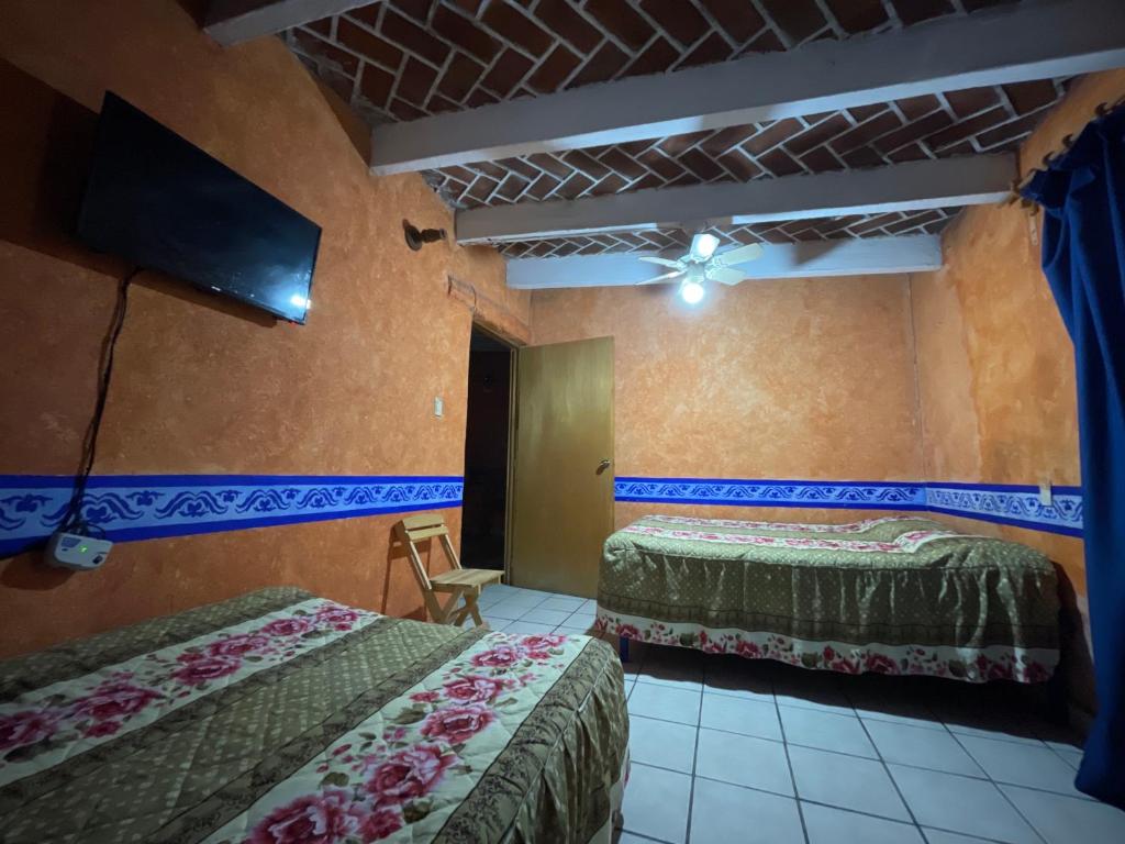 um quarto com 2 camas e uma televisão de ecrã plano em Posada Siete Nogales Tecozautla alojamiento con baño compartido em Tecozautla