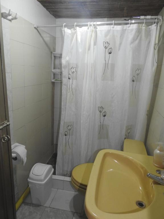 La salle de bains est pourvue d'un lavabo jaune et d'un rideau de douche avec des fleurs. dans l'établissement Refugio ecológico Villa Mercedes, à San Antonio del Tequendama