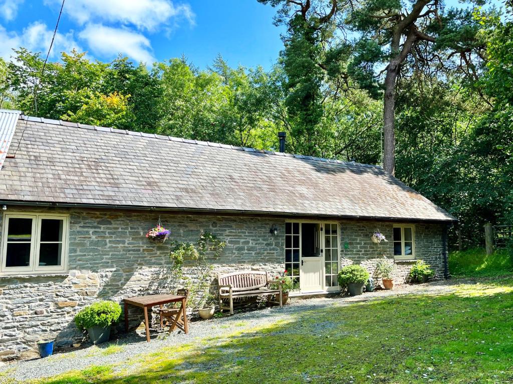 a stone cottage with a bench and a table at Drovers Retreat in Llandrindod Wells