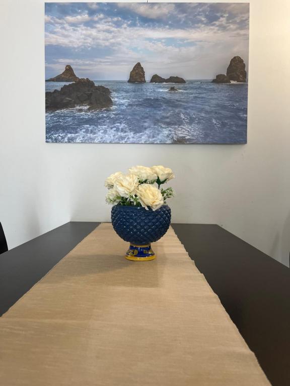 un vase avec des fleurs assis sur une table devant un tableau dans l'établissement Amuri di casa Scogliera, à Catane