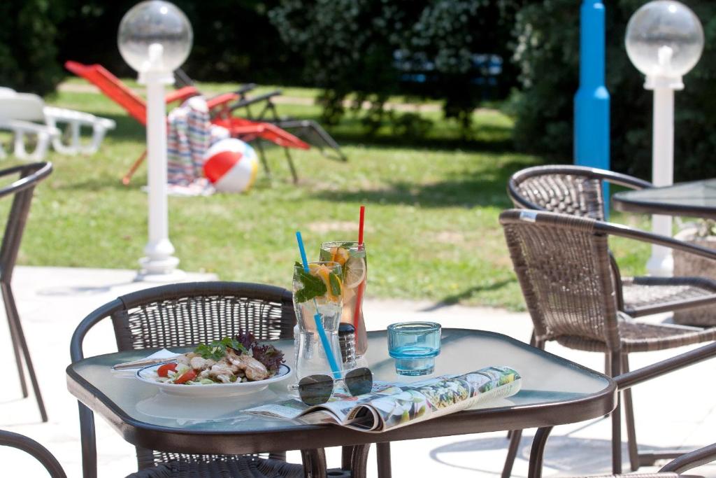 einen Tisch mit einem Teller mit Speisen und Getränken darauf in der Unterkunft Hotel Holiday Csopak in Csopak