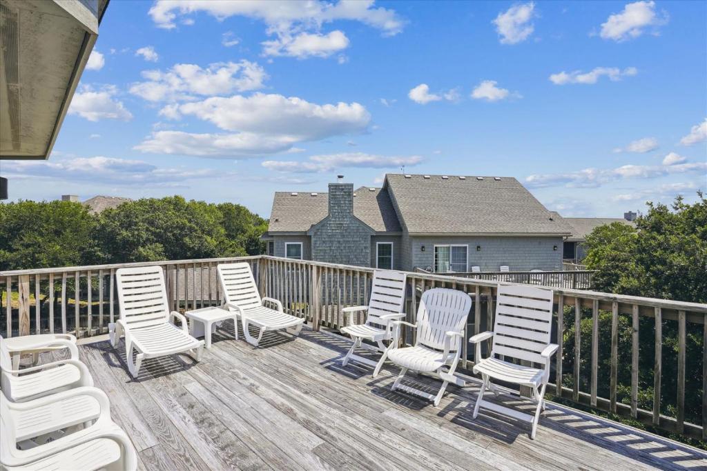 a deck with white chairs and a house at The Glane at Ships Watch in Duck