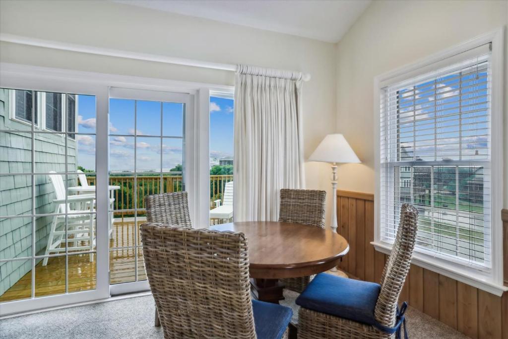 a dining room with a table and chairs and a balcony at The Powell at Ships Watch in Duck