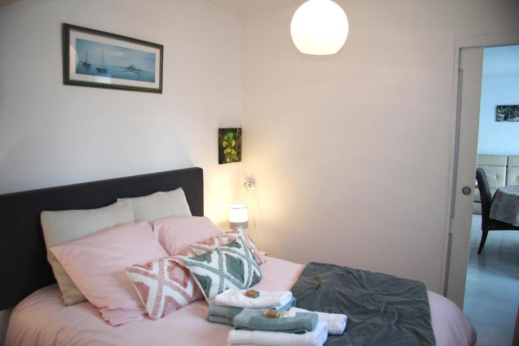 a bedroom with a pink bed with towels on it at Logement agréable et tranquille in Fontenay-Trésigny