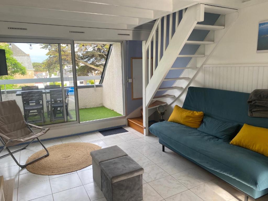 a living room with a blue couch and stairs at Appartement Duplex, Résidence Victoria, à 2min de la Grande Plage in Quiberon