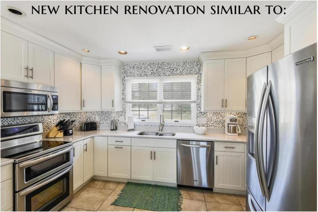 a kitchen with white cabinets and a stainless steel refrigerator at The Shabedge at Ships Watch in Duck