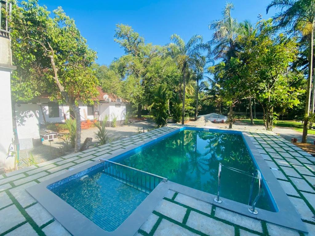 a swimming pool in a backyard with trees at Brookside Heritage Resort in Kumarakom