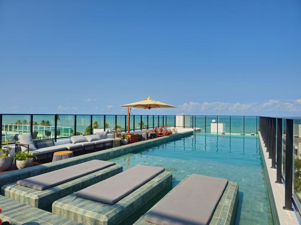 a swimming pool with lounge chairs and an umbrella at Lindo Flat no Jardim Oceania - Get One in João Pessoa