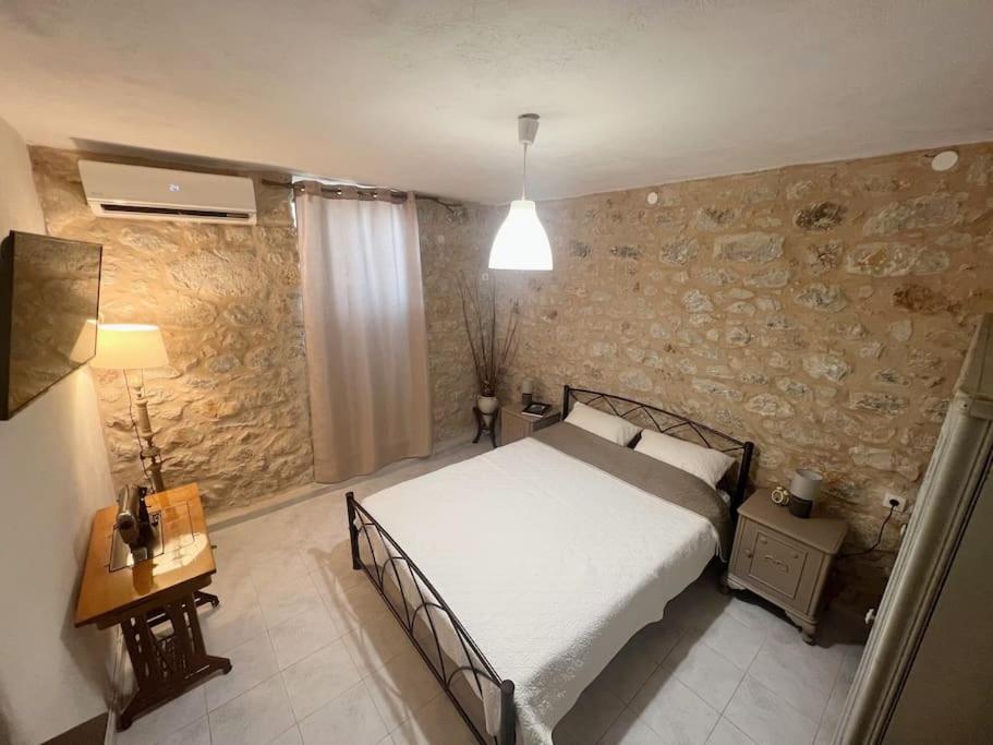 a bedroom with a bed and a stone wall at Λαγκάδι Μάνης in Koíta