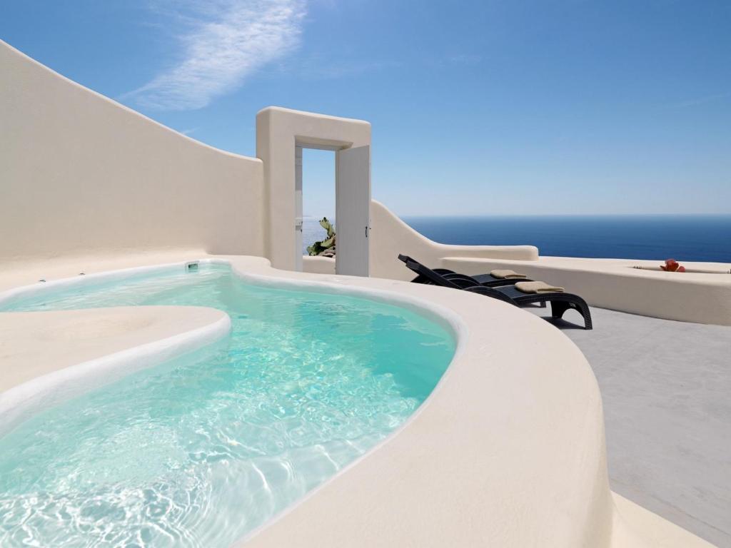 una piscina in una casa con l'oceano sullo sfondo di Dome Santorini Resort a Imerovigli