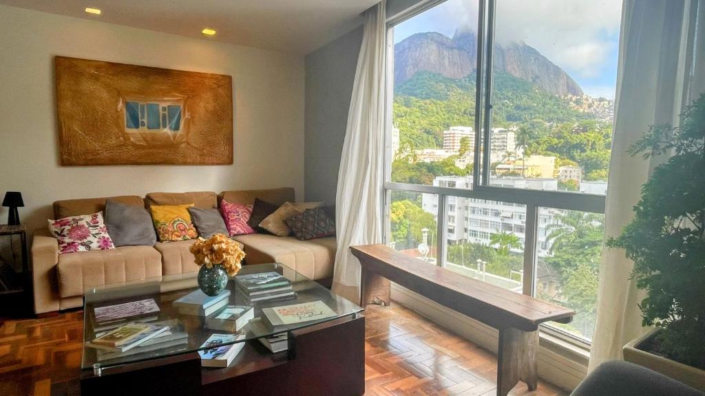 uma sala de estar com um sofá e uma janela grande em Amplo e iluminado apartamento na Gávea no Rio de Janeiro