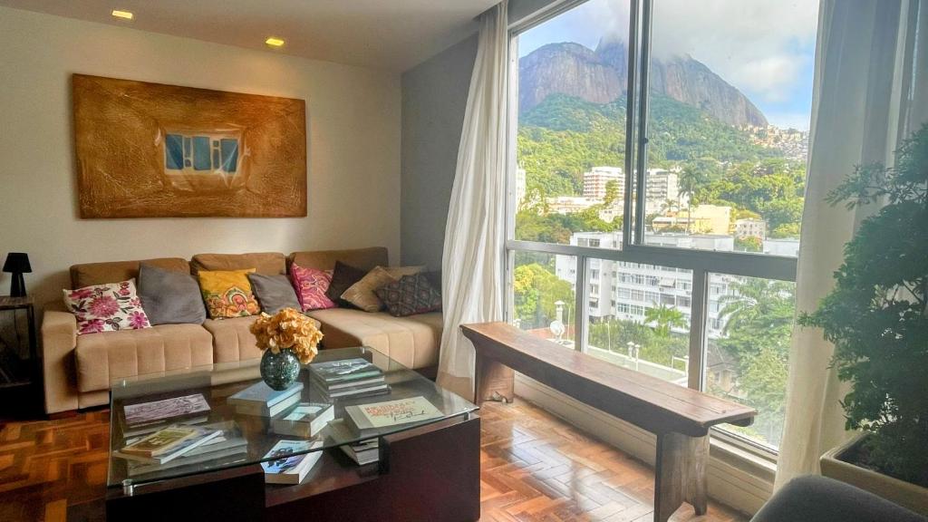 uma sala de estar com um sofá e uma grande janela em Amplo e iluminado apartamento na Gávea no Rio de Janeiro