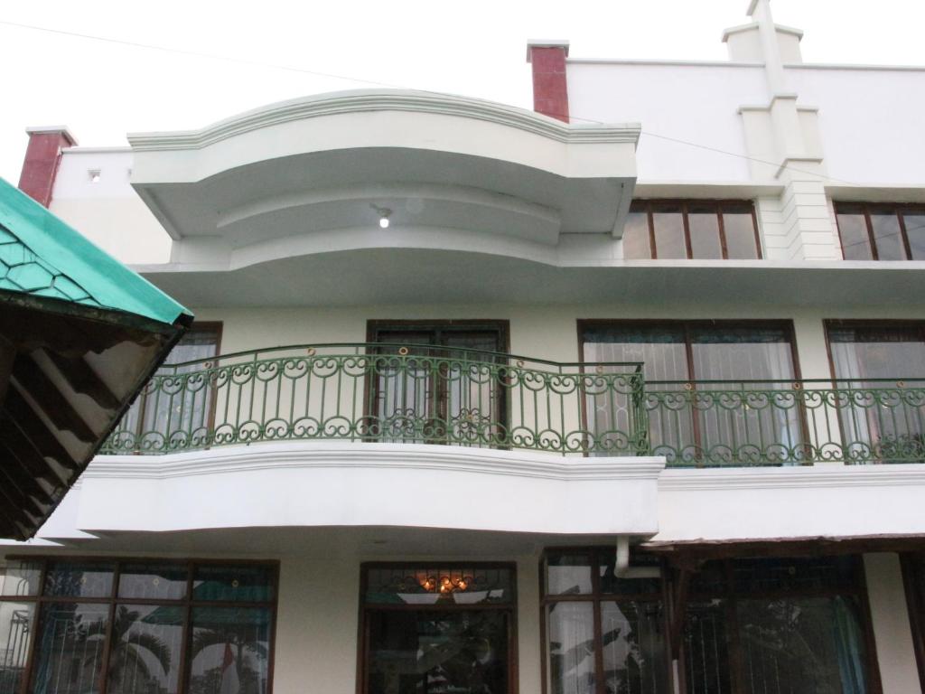 un edificio blanco con un balcón con una cruz. en Villa Hijau Bandungan en Bandungan