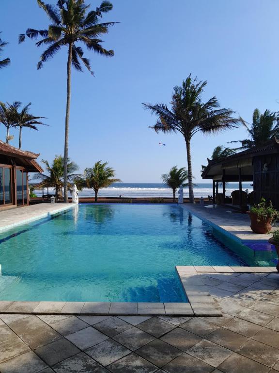 uma piscina ao lado de uma praia com palmeiras em Bali Hai Island Resort em Balian