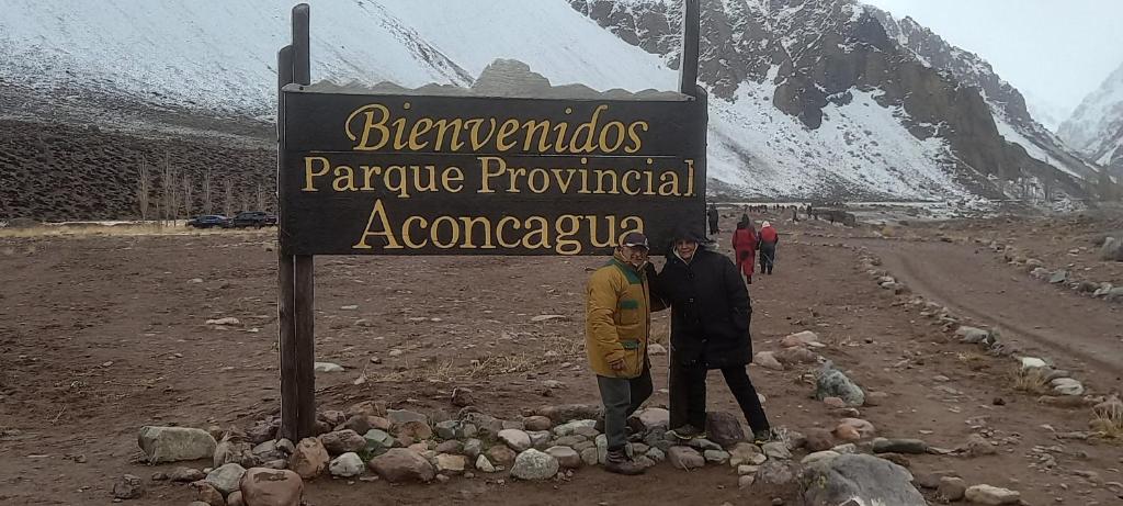 two men standing next to a sign on a mountain at Aires del Montura in Uspallata