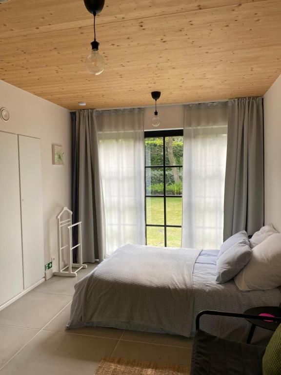 a bedroom with a bed and a large window at de graslelie in Schoten