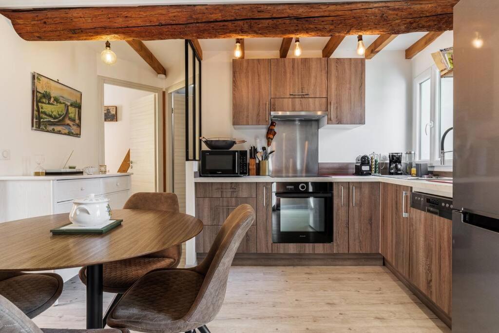 een keuken met een houten tafel en stoelen en een tafel en een aanrecht bij Cocon dans la vieille ville in Villefranche-sur-Mer