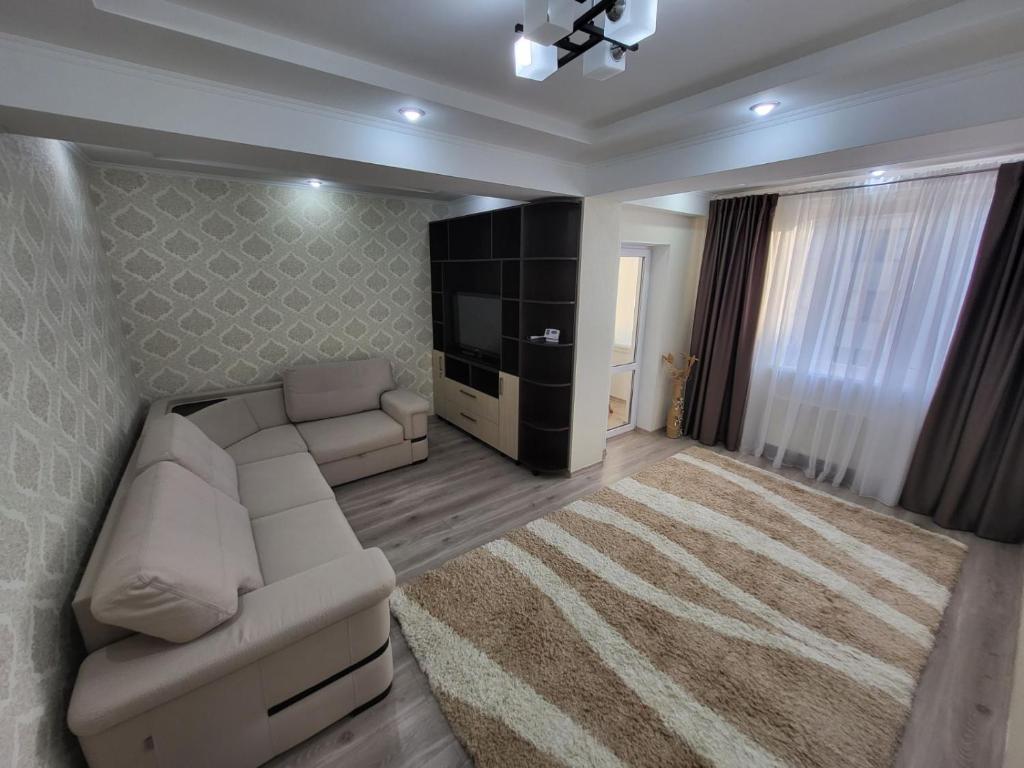ein Wohnzimmer mit einem weißen Sofa und einem TV in der Unterkunft Apartment Buiucani in Chişinău