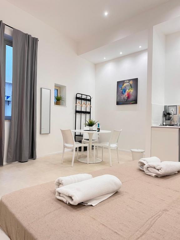 een witte woonkamer met een tafel en stoelen bij Valguarnera Studio Apartments in Palermo