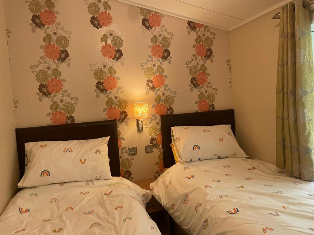 a bedroom with two beds and a light on the wall at 3 Bedroom Lodge - Willows 24, Trecco Bay in Newton