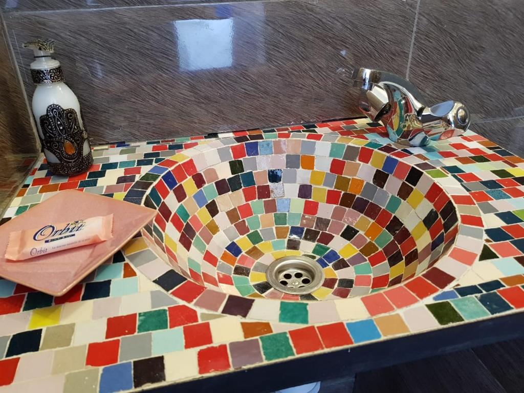 La salle de bains est pourvue d'un lavabo et d'un comptoir en mosaïque coloré. dans l'établissement Dar Suncial, à Marrakech