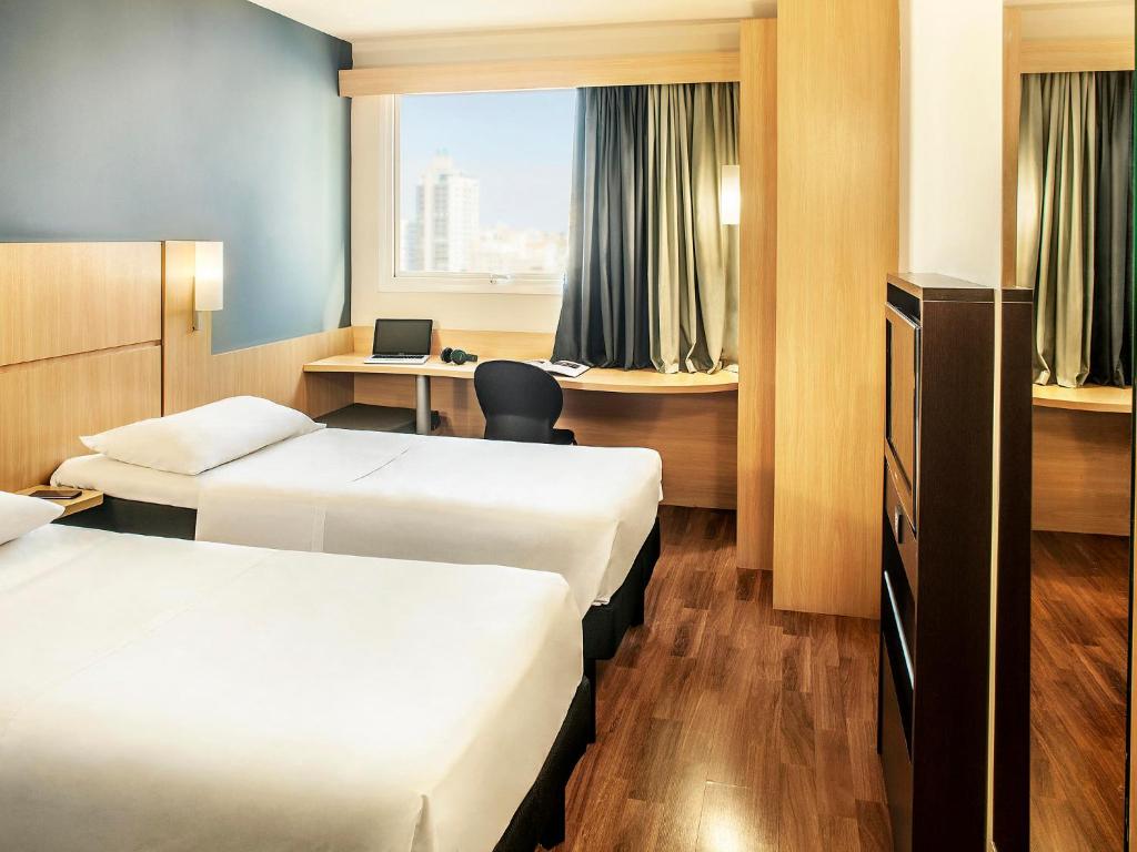 una camera d'albergo con 2 letti e una scrivania di ibis Belo Horizonte Savassi a Belo Horizonte
