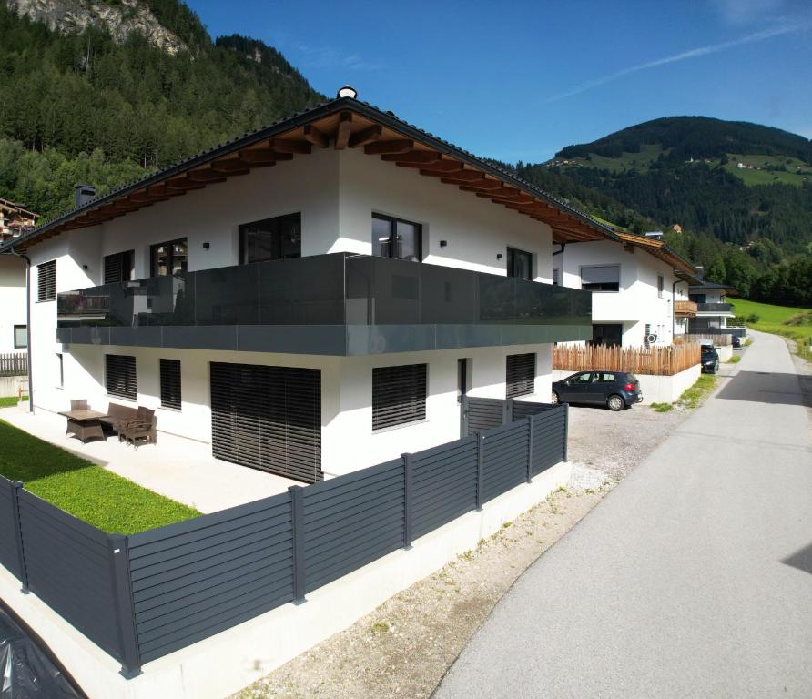una casa blanca con una valla negra en Apart Alpenherz, en Schwendau