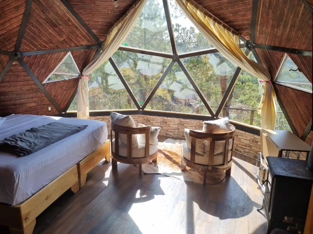 a bedroom with a bed and two chairs in a room at Glamping Town in Otinapa