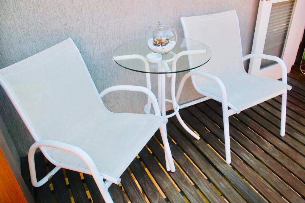 2 sillas blancas y una mesa de cristal en una habitación en No Centro de Gramado em condomínio encantador, en Gramado